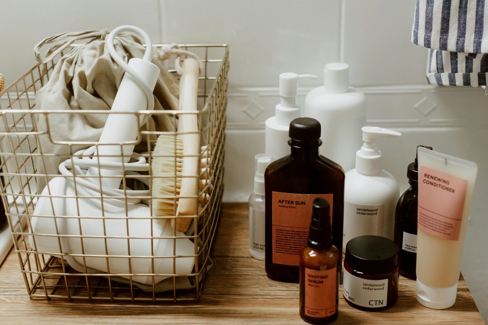 Neatly arranged bathroom toiletries and storage items on a wooden surface, featuring cosmetics and a hair dryer.