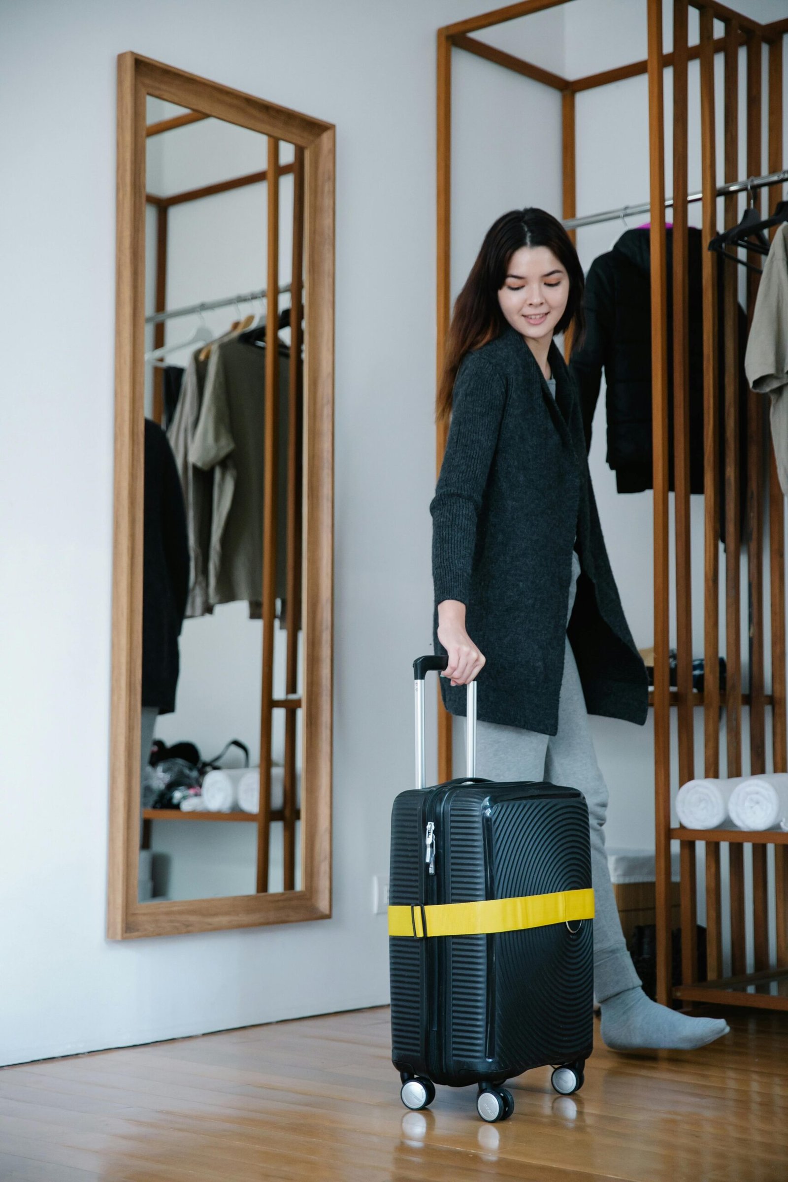 Smiling woman holding suitcase, preparing for a journey in a modern home setting.